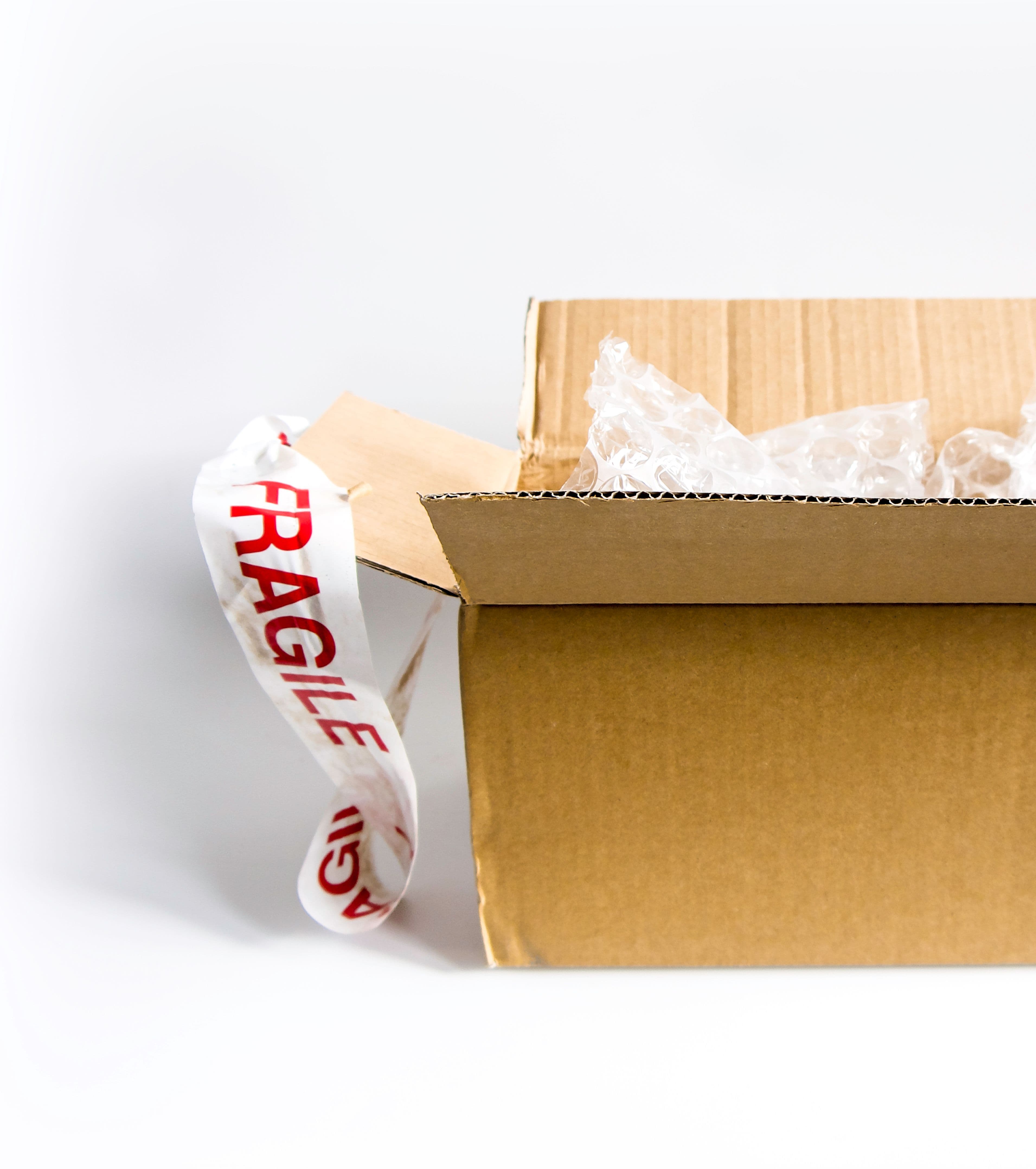 An open cardboard parcel padded with bubble wrap, with fragile tape alongside.